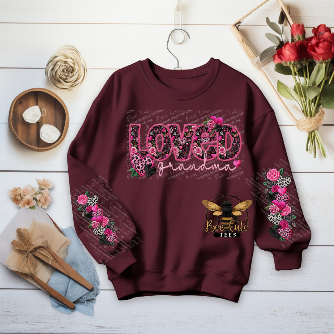 Maroon sweatshirt with floral and text design on a wooden surface with decorative items.