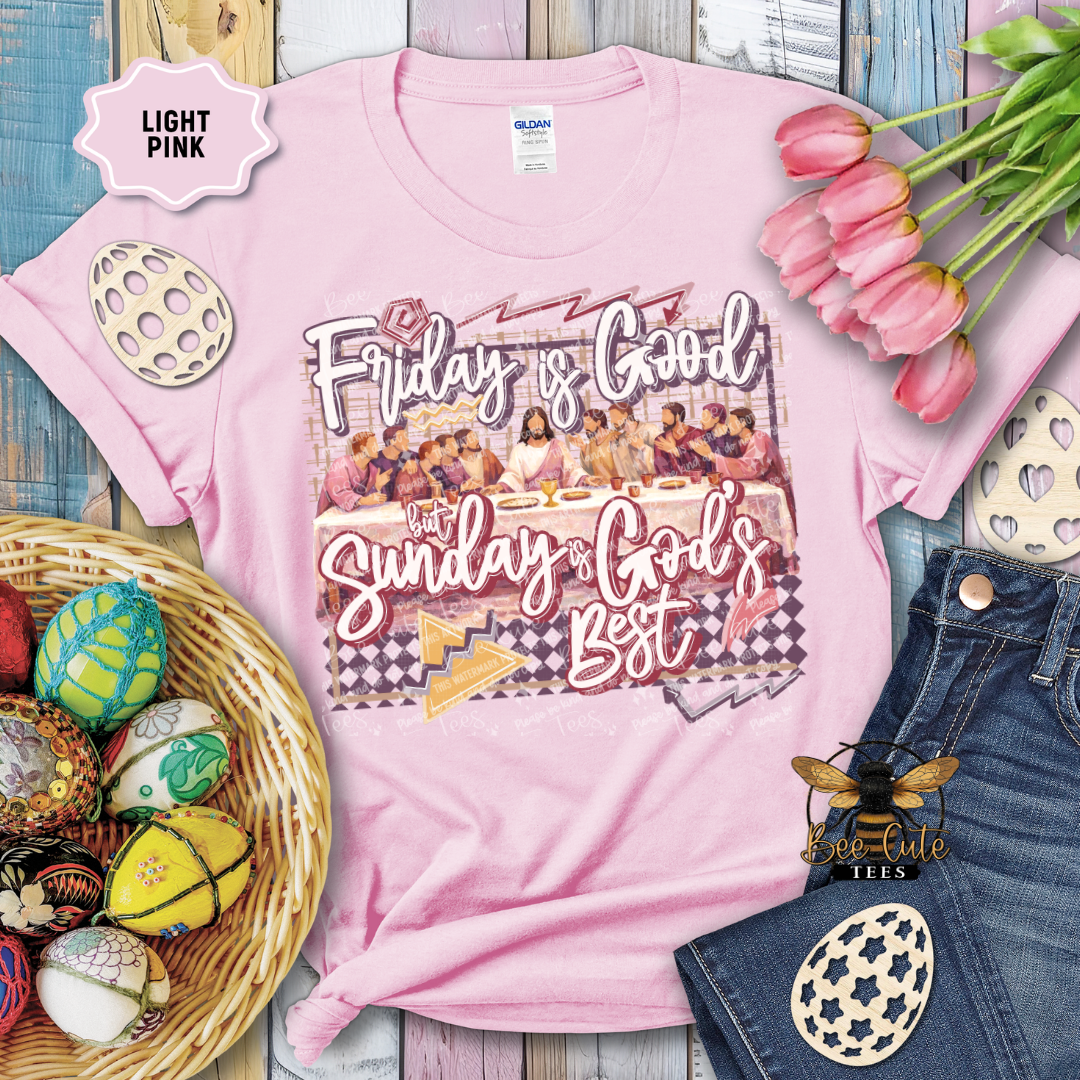 Pink t-shirt with 'Friday is Good, Sunday is God's Best' design, surrounded by Easter decorations on a wooden surface.