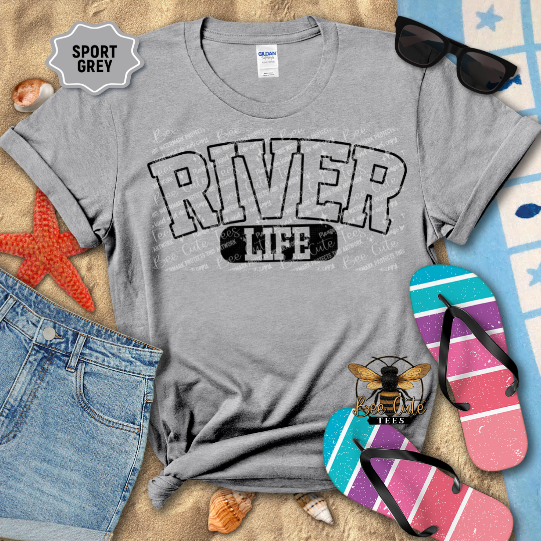 Gray t-shirt with 'River Life' design on a beach-themed background with sunglasses, flip-flops, and denim shorts.