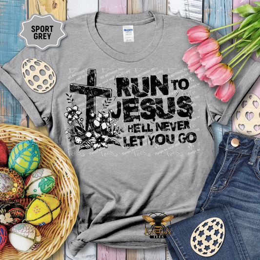 Gray t-shirt with 'Run to Jesus, Hell Never Let You Go' design on a wooden surface with Easter decorations.