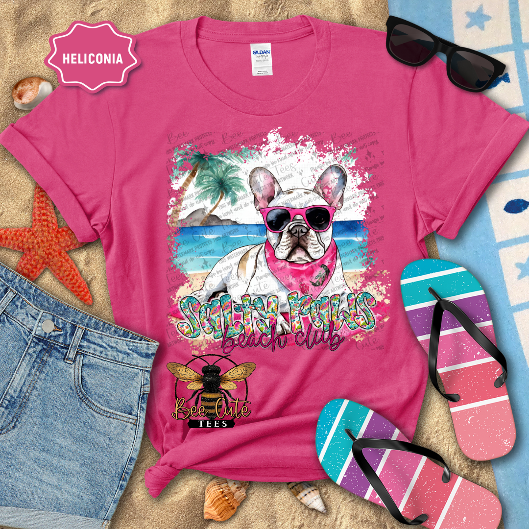 Pink t-shirt with a dog graphic and 'Beach Club' text, surrounded by beach accessories.