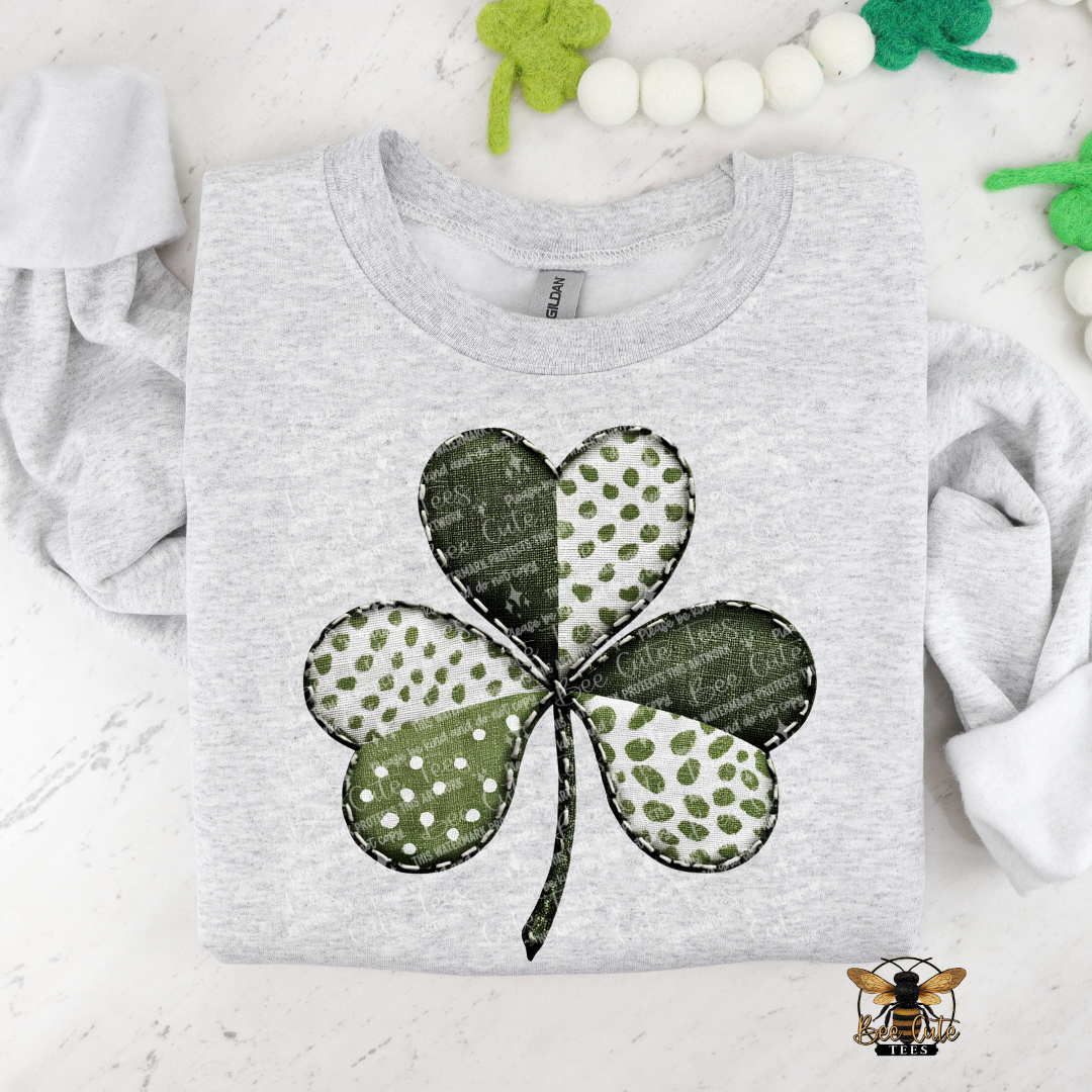Gray t-shirt with a green four-leaf clover design on a white background