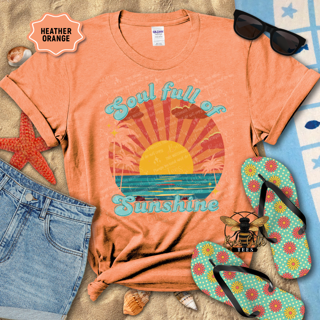 Orange t-shirt with 'Soul full of sunshine' design, sunglasses, jeans, starfish, and flip-flops on a textured surface.