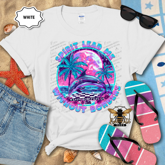 White t-shirt with a colorful graphic design on a sandy surface with flip-flops and sunglasses.