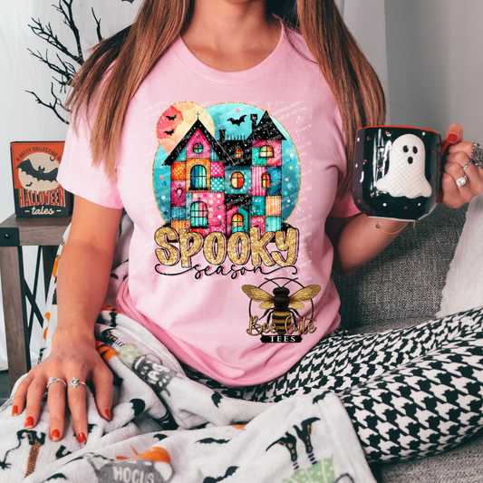 Person wearing a pink t-shirt with a Halloween-themed design, holding a mug with a ghost design.