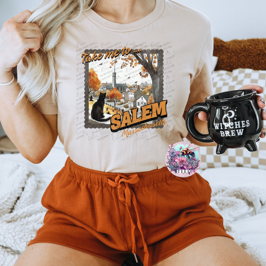 Person wearing a t-shirt with 'Take me to Salem' design and holding a mug with 'Witches Brew' text.