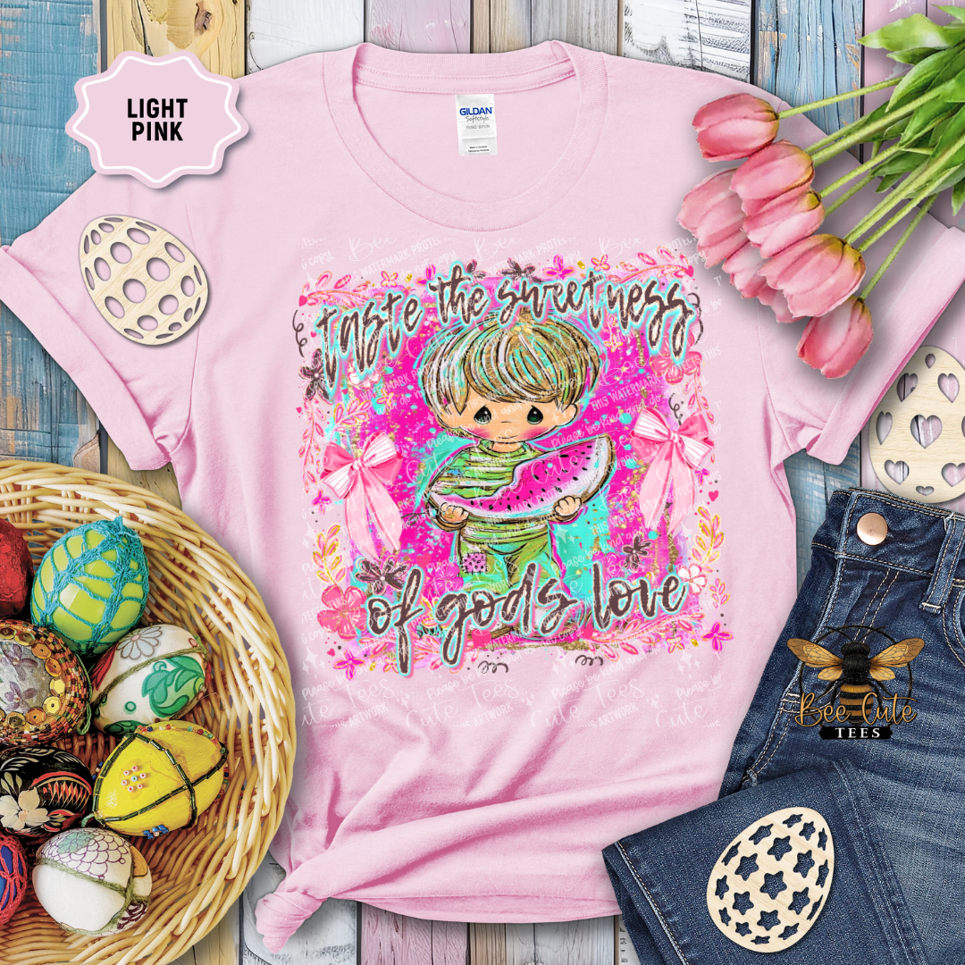 Pink t-shirt with a colorful graphic and text, surrounded by Easter decorations on a wooden surface.