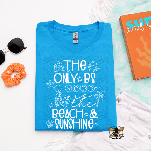Blue t-shirt with beach-themed text on a white surface with accessories.