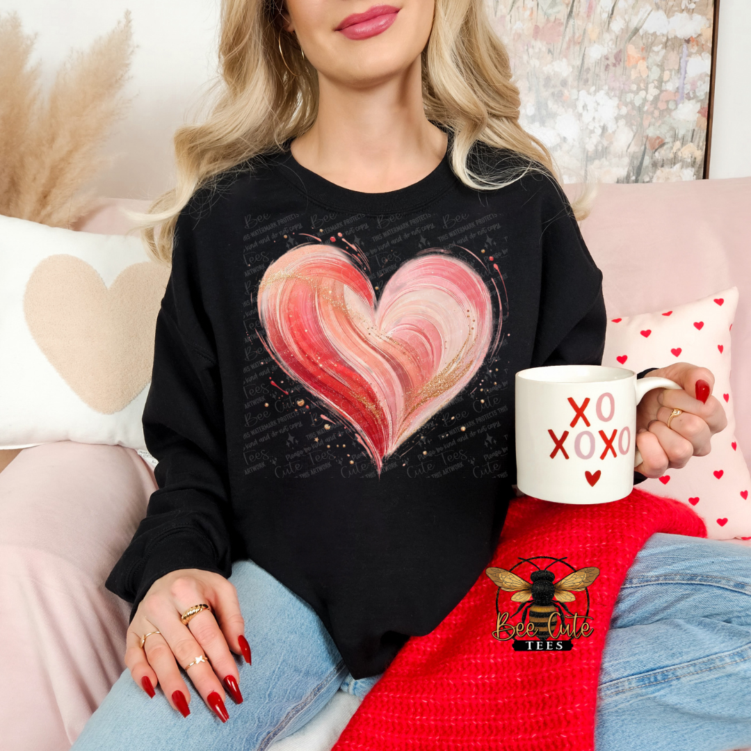Woman wearing a black sweatshirt with a pink heart design, holding a mug with 'XO XO XO' text, sitting on a couch.