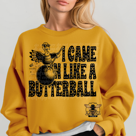 A woman wearing a mustard yellow crewneck sweatshirt with a black graphic print that reads 'I CAME IN LIKE A BUTTERBALL' alongside a bee logo.