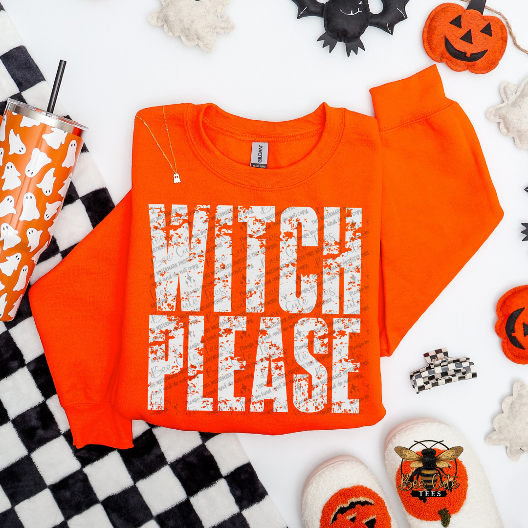 An orange crewneck sweatshirt with 'WITCH PLEASE' printed in distressed white letters, styled in a flat lay with Halloween props including a pumpkin, witch hat, checkered blanket, and slippers on a white background.