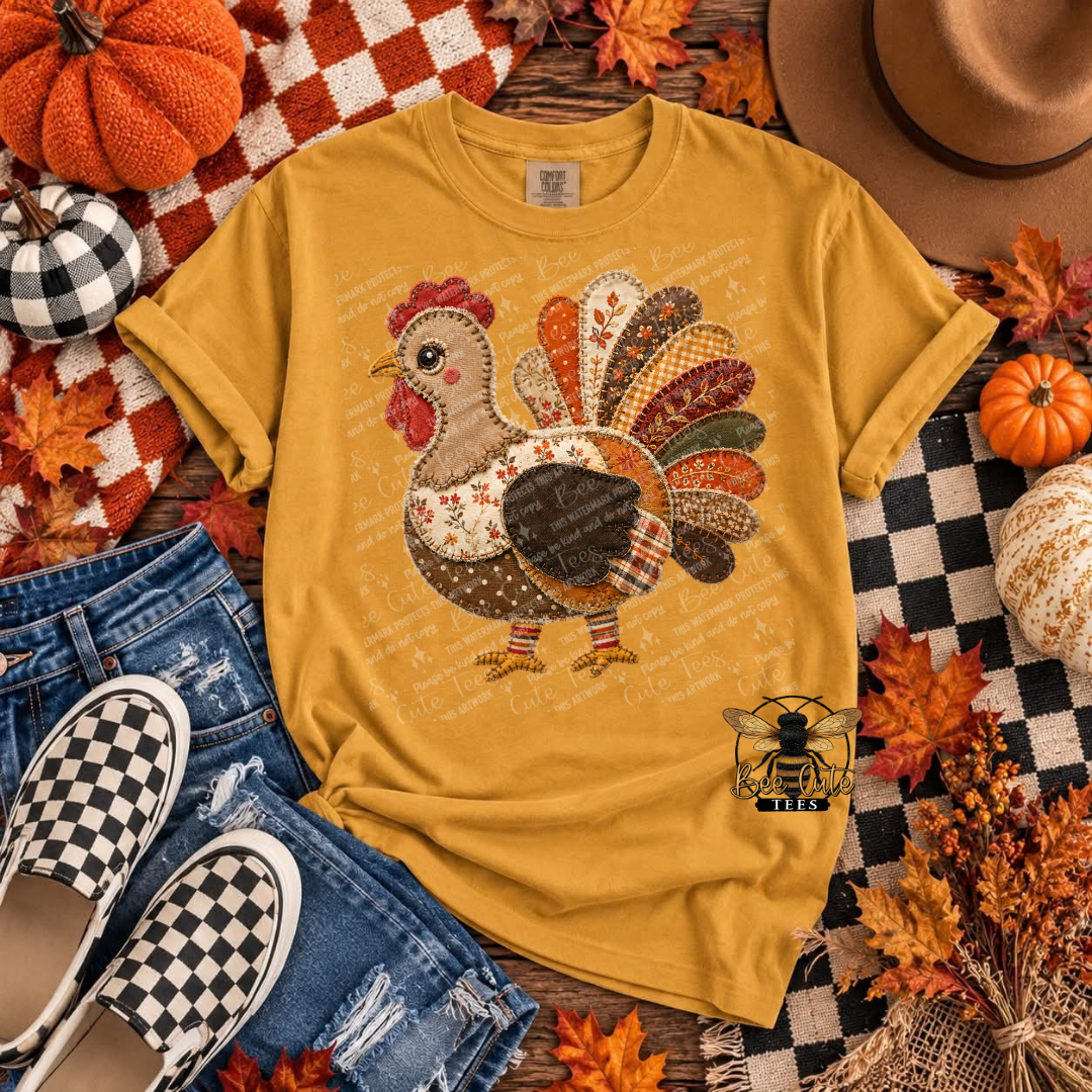 A mustard yellow graphic t-shirt featuring a patchwork-style turkey design, styled in a flat lay with jeans, checkered slip-on shoes, pumpkins, autumn leaves, and a hat.