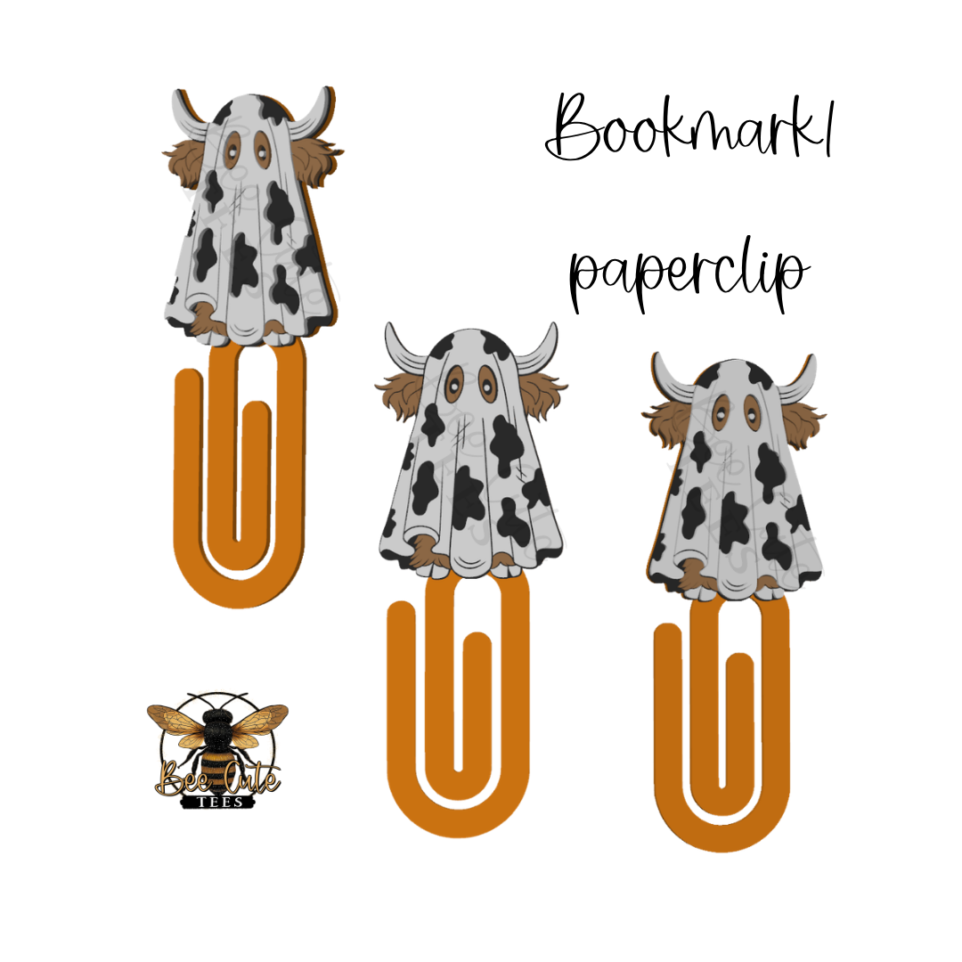 Three novelty paperclip bookmarks on a white background, each shaped like a cow with a black-and-white spotted pattern, brown horns and ears, and a gold-toned clip. One bookmark shows a bee logo with the words 'BEE CUTE TEES' beneath it.