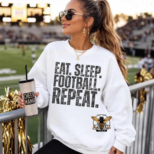 A woman in a white sweatshirt with 'EAT. SLEEP. FOOTBALL. REPEAT.'