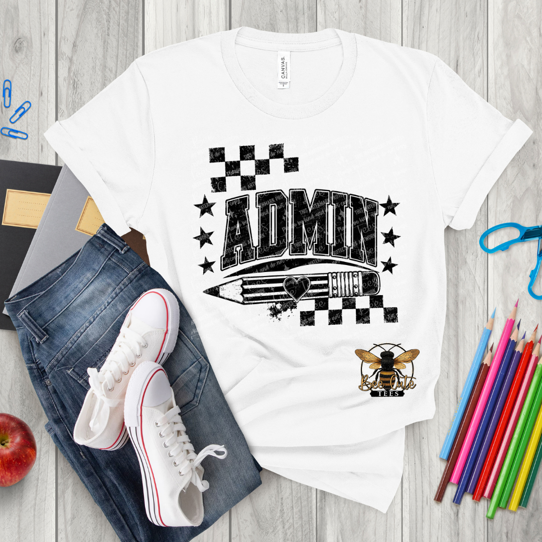 A white graphic t-shirt featuring a black and gray 'ADMIN' pencil design, styled in a flat lay with blue jeans, white sneakers, colored pencils, and an apple on a gray wood plank background.