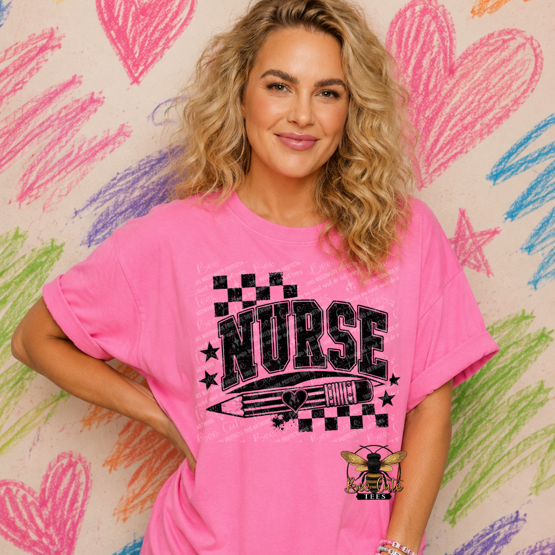A woman with blonde curly hair wearing a bright pink graphic t-shirt that says 'NURSE ' in black with a bee logo, posing in front of a heart-drawn chalkboard wall.