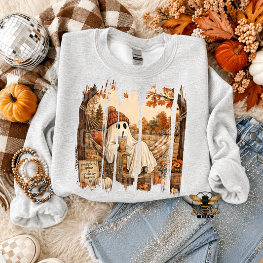 A light heather gray crewneck sweatshirt laid flat on a cozy autumn-themed background. The sweatshirt features a graphic print of a friendly ghost sitting in a hammock with a pumpkin slice, surrounded by fall leaves and trees.