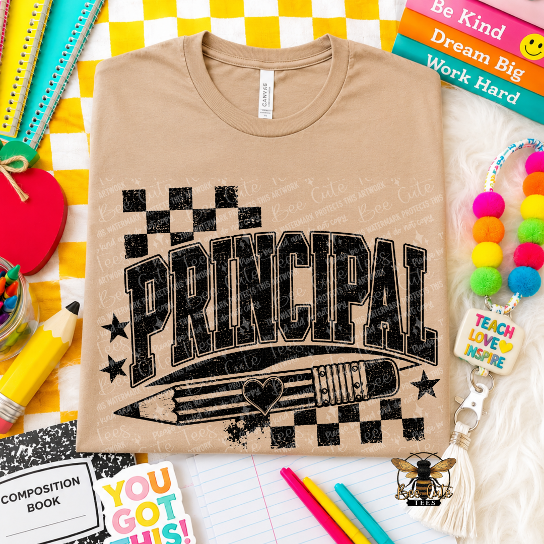 A beige short-sleeve t-shirt with a black graphic reading 'PRINCIPAL' over a pencil and checkerboard design, styled in a school-themed flat lay with notebooks, pens, and colorful accessories.