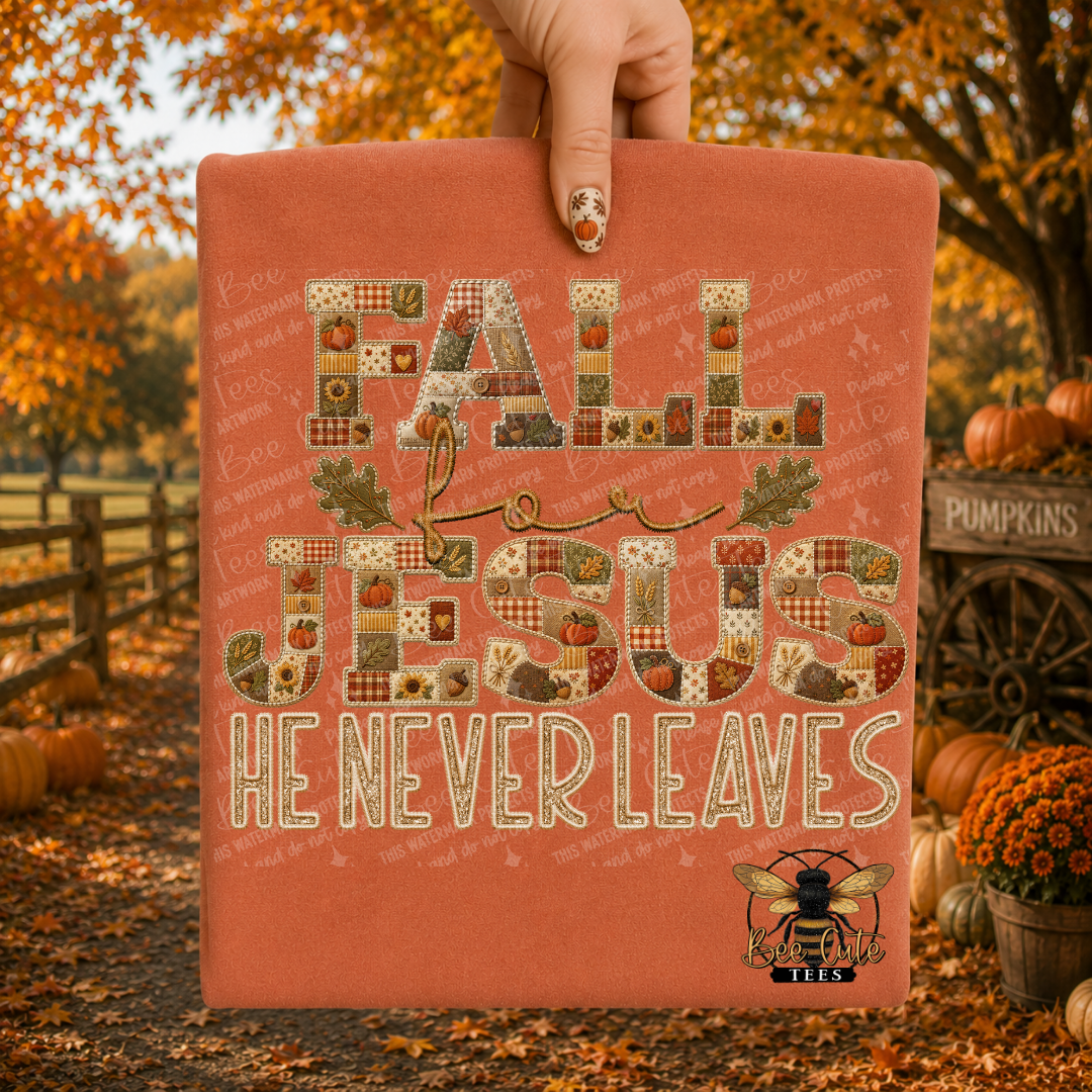 A hand holds a folded t-shirt with a fall-themed graphic that reads 'FALL JESUS HE NEVER LEAVES' in patchwork-style lettering. The shirt is a warm terracotta color, and the background shows an autumn outdoor scene with pumpkins, orange foliage, and a wooden fence.
