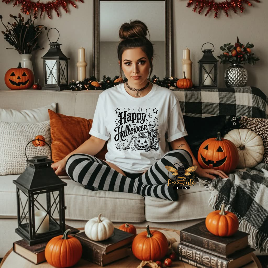 A woman sits on a beige couch in a decorated living room, wearing a white graphic T-shirt that says 'Happy Halloween' with a jack-o'-lantern illustration, paired with black-and-white striped tights. Pumpkins, lanterns, pillows, and fall decor surround her.