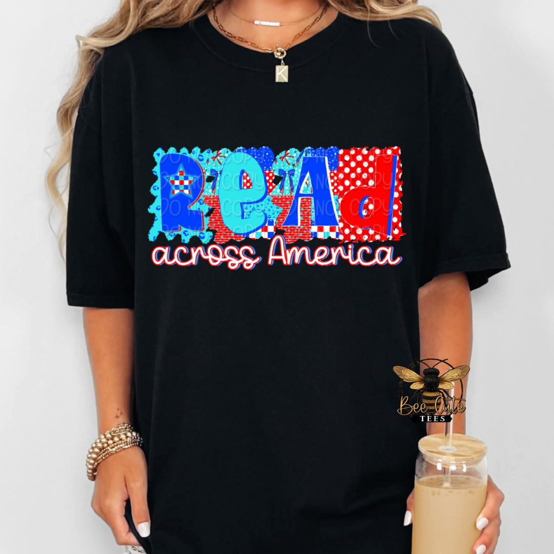 Person wearing a black t-shirt with colorful text 'READ across America' holding a drink.