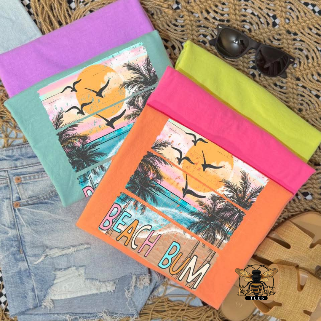 Colorful beach-themed t-shirts with 'Beach Bum' text on a textured surface.
