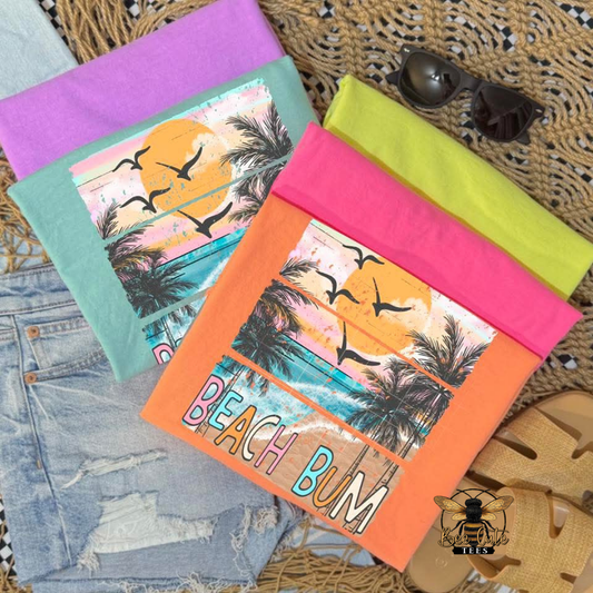 Colorful beach-themed t-shirts with 'Beach Bum' text on a textured surface.