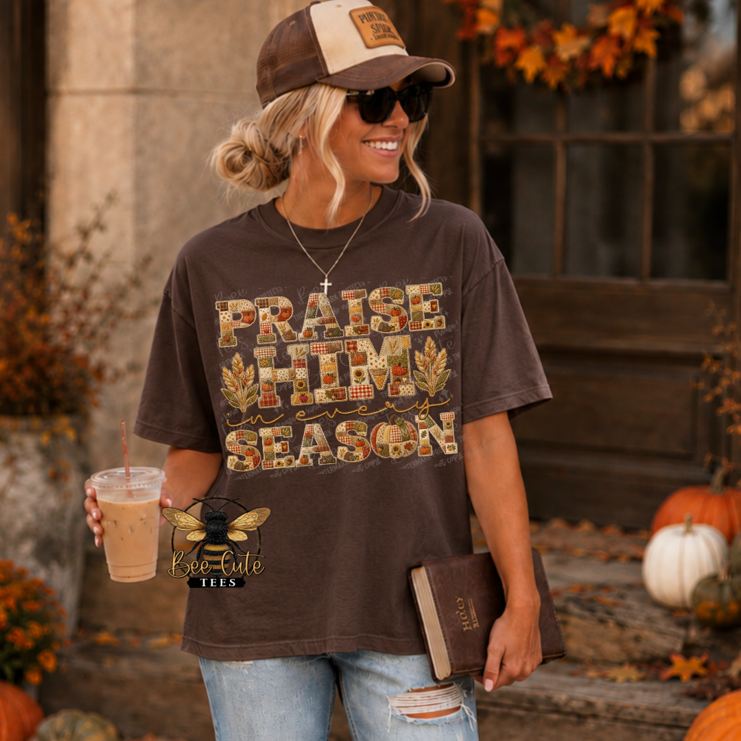 Woman wearing a dark brown graphic tee featuring the phrase “Praise Him in Every Season” in fall-inspired faux patchwork and embroidered lettering with pumpkins, sunflowers, autumn leaves, wheat stalks, and warm plaid patterns. She is wearing distressed jeans, sunglasses, and a baseball cap while holding an iced coffee and Bible. Cozy autumn porch setting with pumpkins, fall foliage, and seasonal decorations. Bee Cute Tees logo displayed on the mockup.
