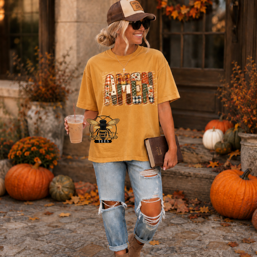A woman stands outdoors in a fall-themed setting wearing a mustard yellow graphic T-shirt with a large 'HAPPY FALL' design and a bee graphic, paired with ripped light-wash jeans and a brown cap.