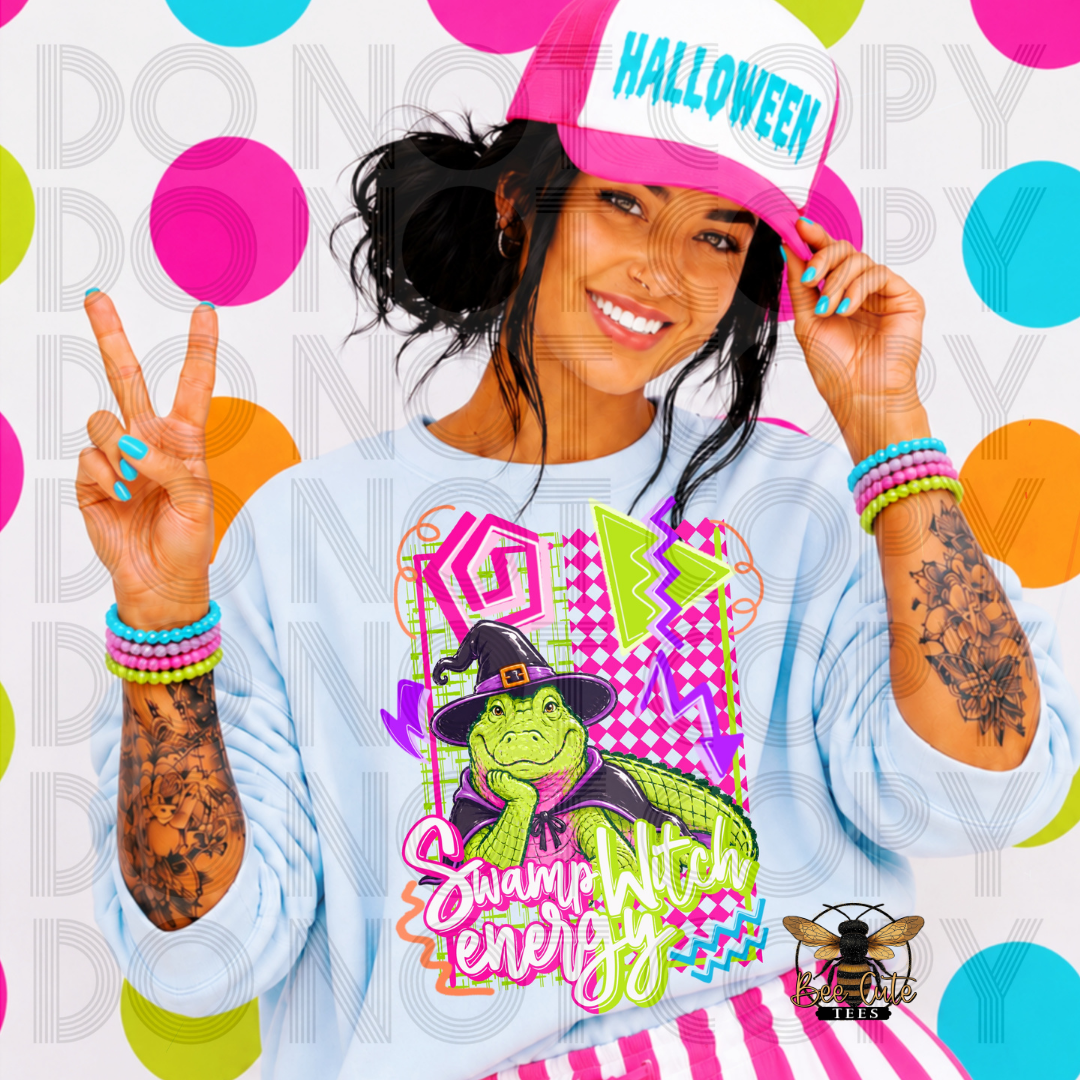 A woman wearing a light blue long-sleeve graphic sweatshirt with a Swamp Witch design, a pink and white 'HALLOWEEN' cap, and colorful beaded bracelets, posing against a vibrant multicolor polka dot background.