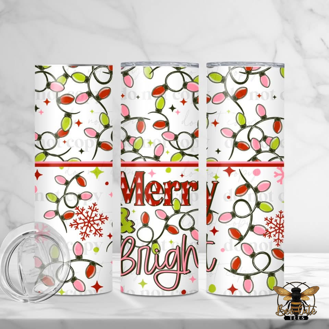 Three white insulated tumblers with a Christmas light pattern in pink, red, green, and orange, featuring 'Merry Bright' text and snowflakes, shown on a white marble background with a clear lid.