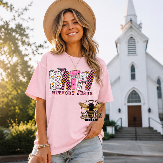 A woman wearing a light pink graphic t-shirt with a bee logo and the text 'BATTY WITHOUT JESUS' stands in front of a white church building.
