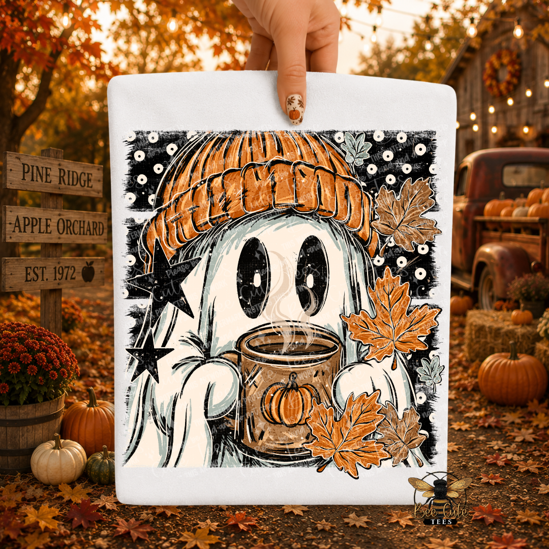 A hand holds a white square sign featuring a whimsical Halloween illustration of a ghost in an orange knit hat, holding a pumpkin mug, surrounded by autumn leaves and stars. The background is a real outdoor fall yard scene with pumpkins, fall leaves, a rustic truck, and a cabin.