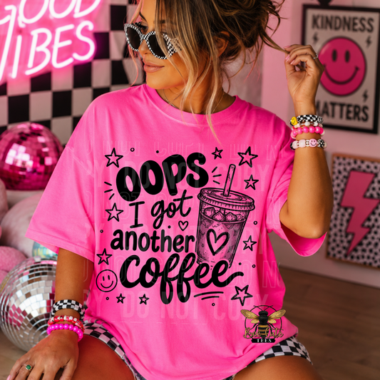 A woman wearing a bright pink graphic t-shirt with the text 'OOPS I got another coffee' and a coffee cup illustration, posed in a decorated room with disco balls and neon signs.