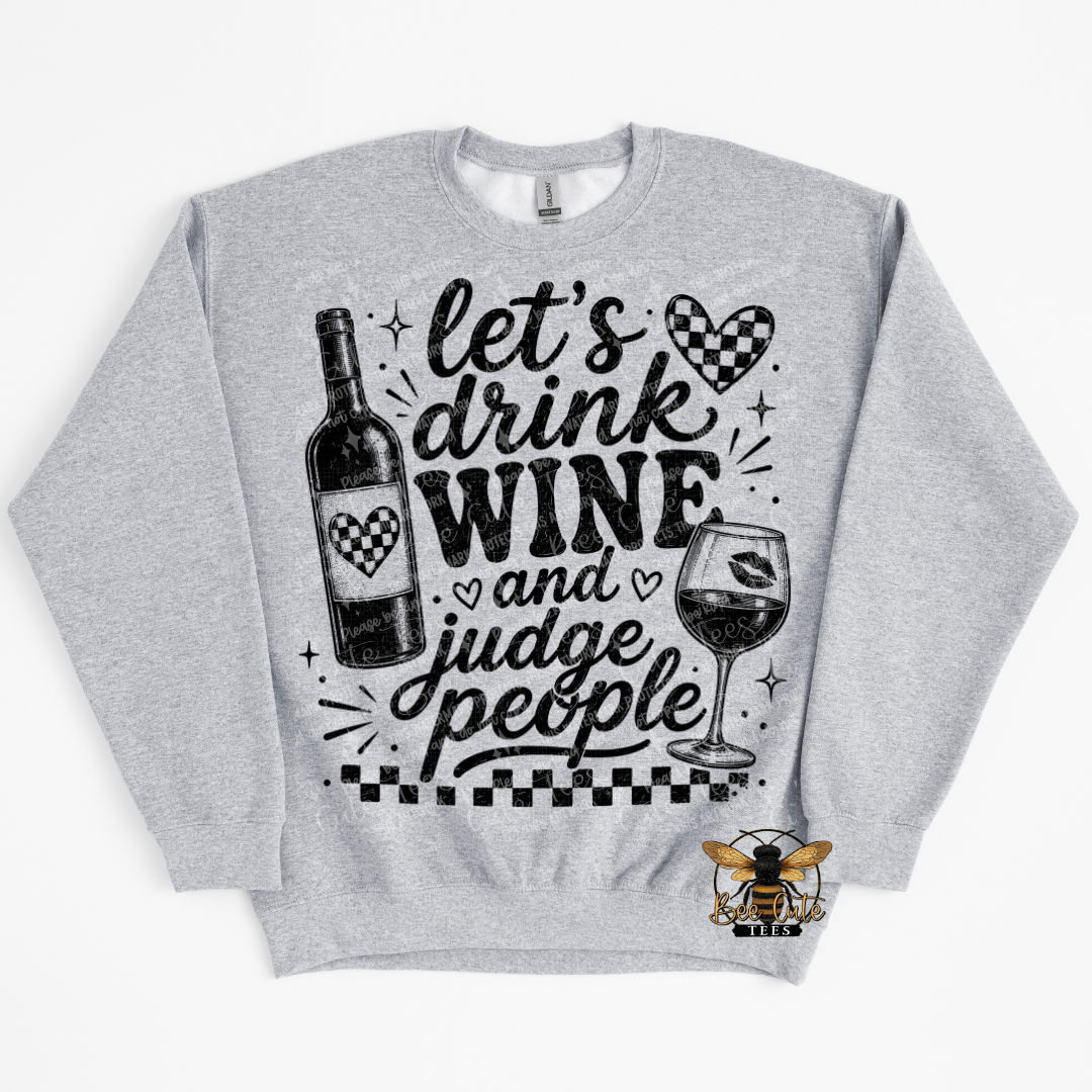 A heather gray crewneck sweatshirt featuring a black graphic print with the text 'let's drink WINE and judge people' alongside illustrations of a wine bottle and wine glass.