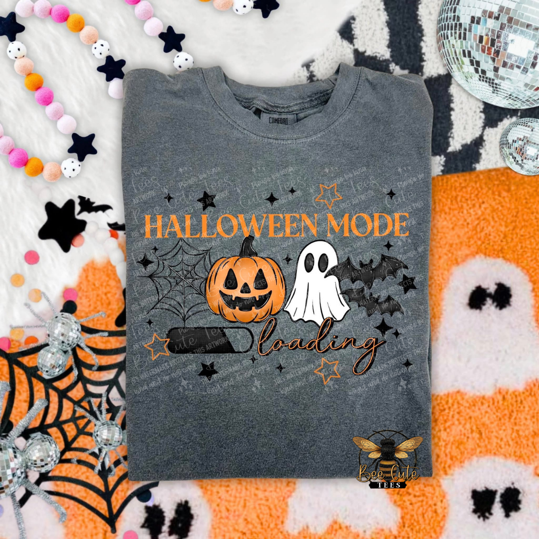 Gray t-shirt with Halloween-themed design featuring a pumpkin, ghost, and bat on a festive background.
