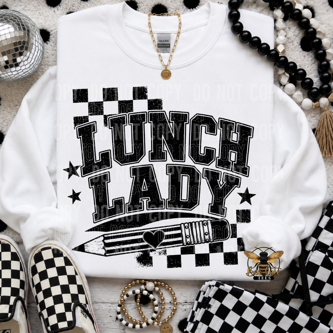 A white sweatshirt laid flat with a black-and-white checkerboard graphic reading “LUNCH LADY” and a pencil illustration. The sweatshirt is styled with black-and-white checkerboard shoes, beaded necklaces, a gold necklace, bracelets, and a matching checkered fabric piece on a textured white surface.