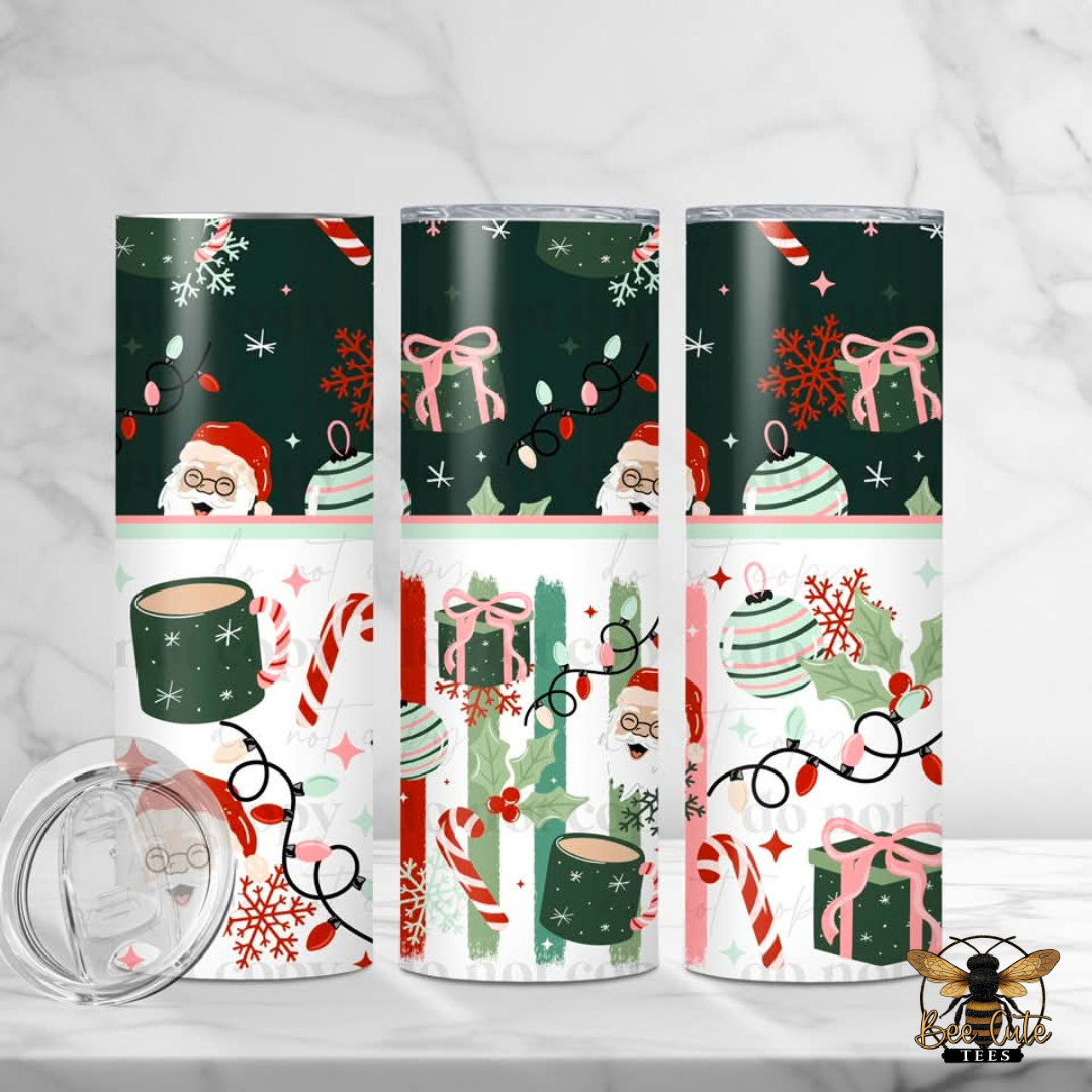 Three insulated tumblers with a Christmas Santa Claus pattern, shown on a white marble surface with a clear lid in the foreground. The design features dark green, white, pink, and red holiday motifs including Santa, candy canes, ornaments, and snowflakes.