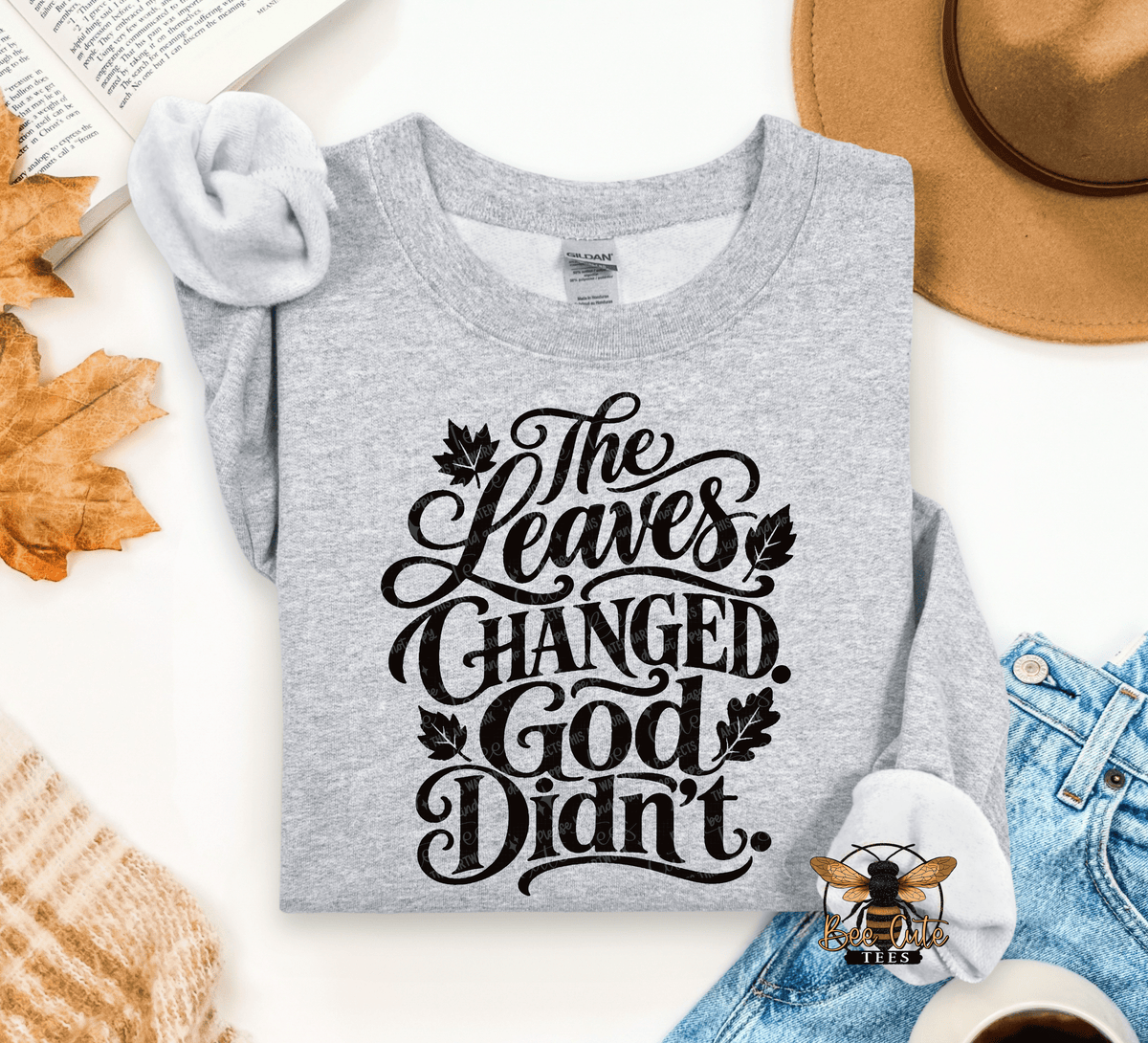A folded heather gray graphic T-shirt with black script text reading 'The Leaves Changed. God Didn't.
