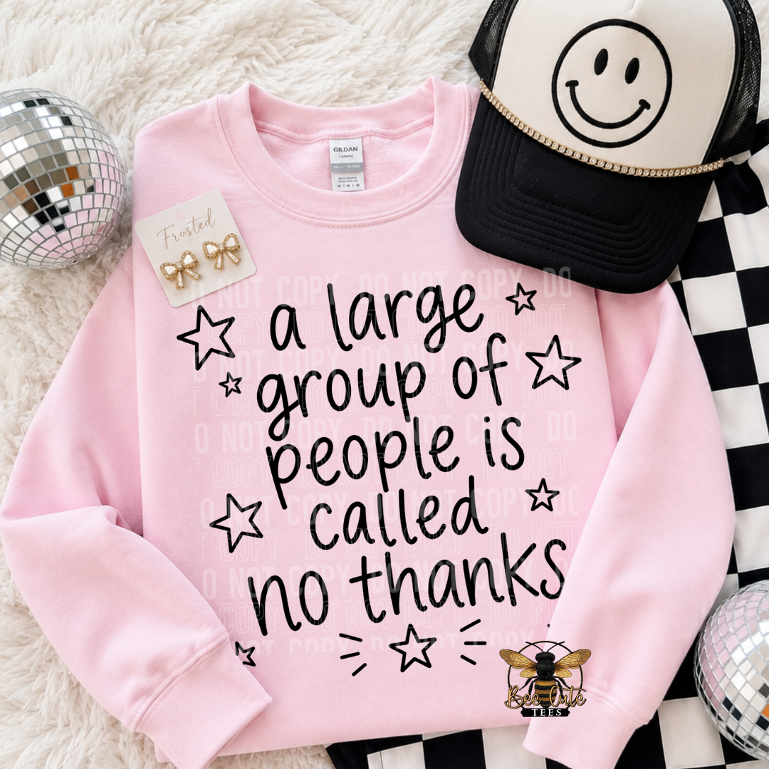 A pink crewneck sweatshirt with the text 'a large group of people is called no thanks' in black, styled in a flat lay with a black and white smiley face trucker hat, gold bow earrings, and disco balls on a white faux fur background.