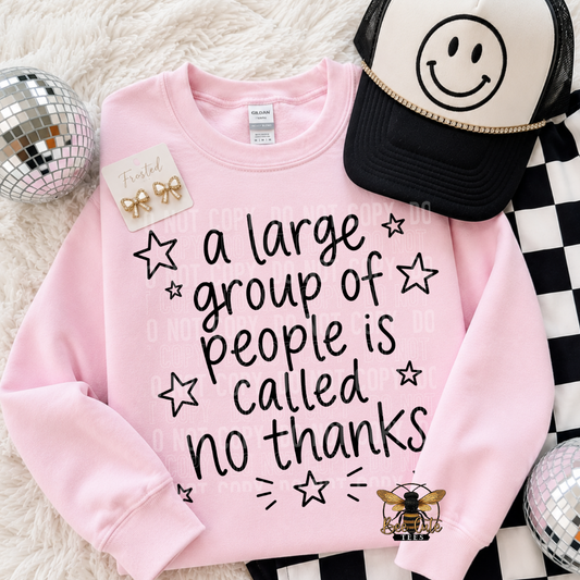 A pink crewneck sweatshirt with the text 'a large group of people is called no thanks' in black, styled in a flat lay with a black and white smiley face trucker hat, gold bow earrings, and disco balls on a white faux fur background.