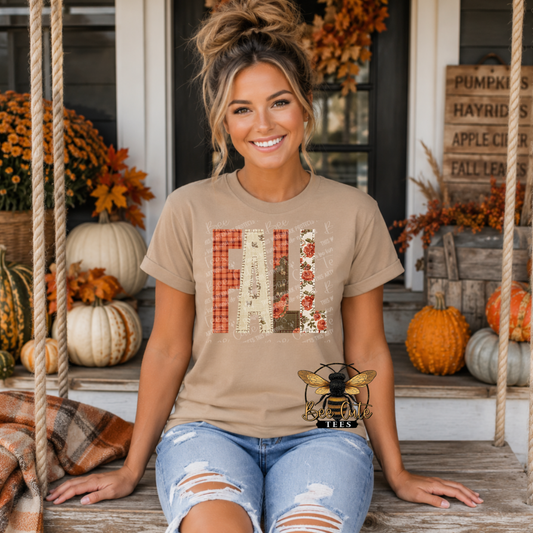 A woman sitting on a porch swing wearing a beige graphic t-shirt with 'FALL' spelled out in autumn-themed patchwork letters, paired with distressed blue jeans.
