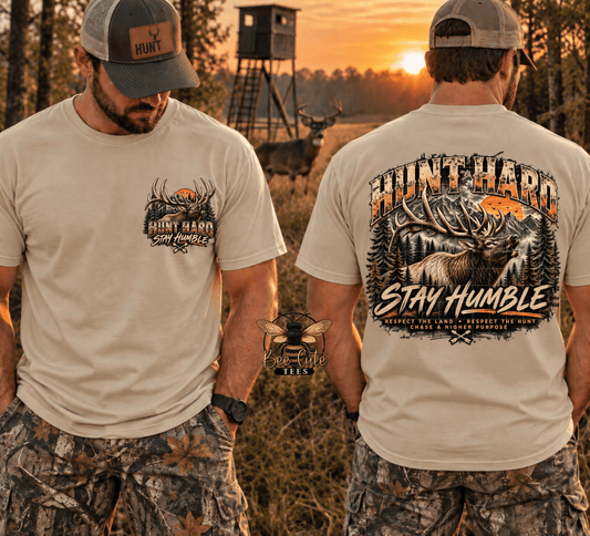 Two men shown outdoors at sunset modeling a beige graphic T-shirt, with one view of the front chest graphic and one view of the large back graphic. The shirt reads “HUNT HARD Stay Humble” with a deer and antler design.