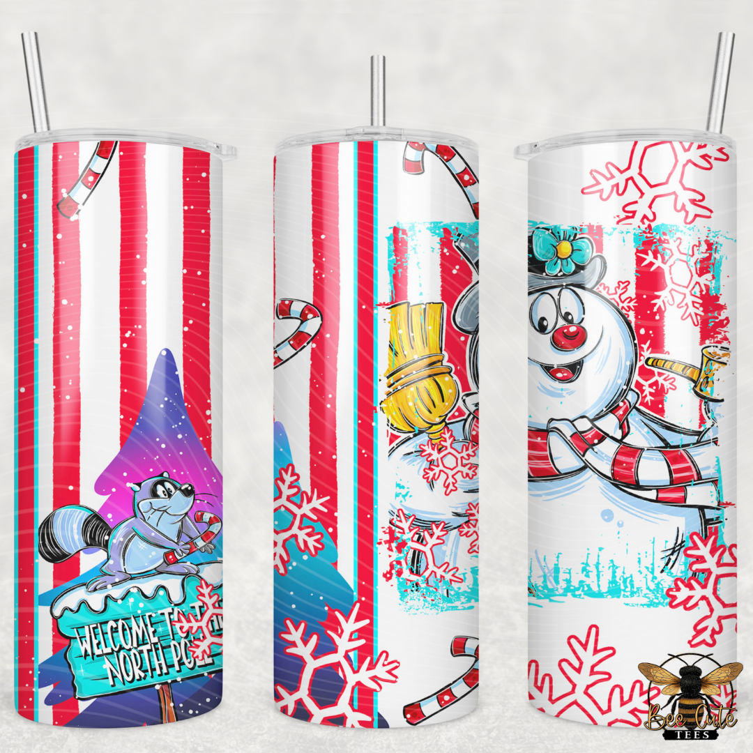 Three insulated tumbler cups with clear lids and straws, each showing a different festive holiday wrap design. The designs include red-and-white vertical stripes with candy canes and snowflakes, a raccoon holding a sign that reads 'Welcome to North Pole,' a snowman with a red-and-white striped scarf and hat, and red snowflakes on a white background.