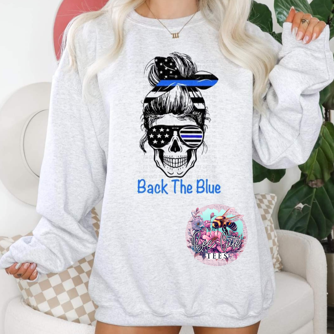 A gray sweatshirt with a graphic print of a skull wearing sunglasses and a 'Blue Lives Matter' badge, alongside the text 'BACK THE BLUE'.