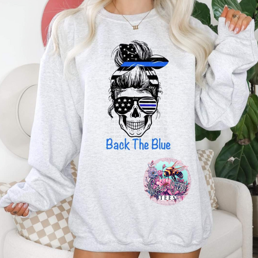 A gray sweatshirt with a graphic print of a skull wearing sunglasses and a 'Blue Lives Matter' badge, alongside the text 'BACK THE BLUE'.