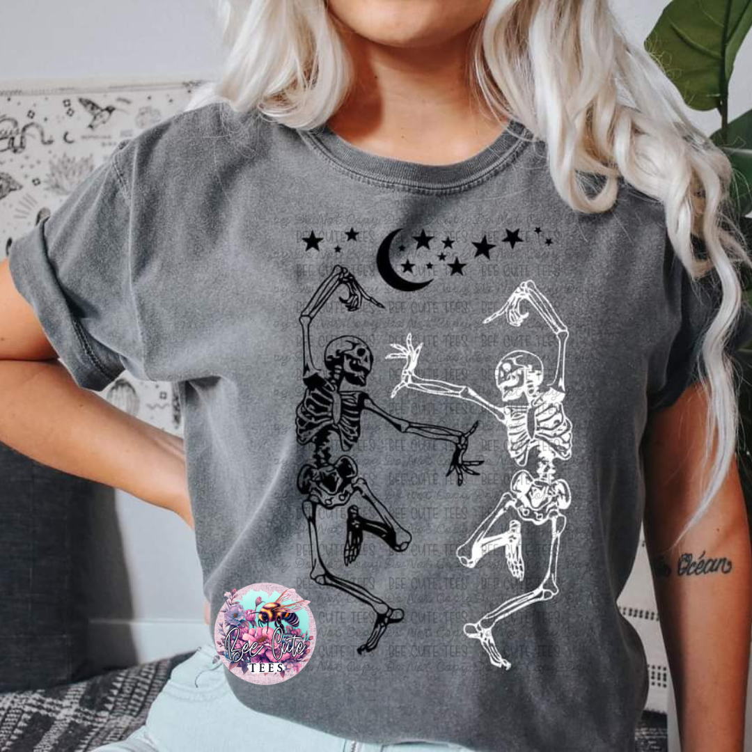 A gray short-sleeved t-shirt with a black and white graphic design of dancing skeletons, moon, and stars.