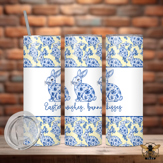 Three tumblers with blue and white floral patterns and Easter-themed text on a wooden surface with a brick wall background.