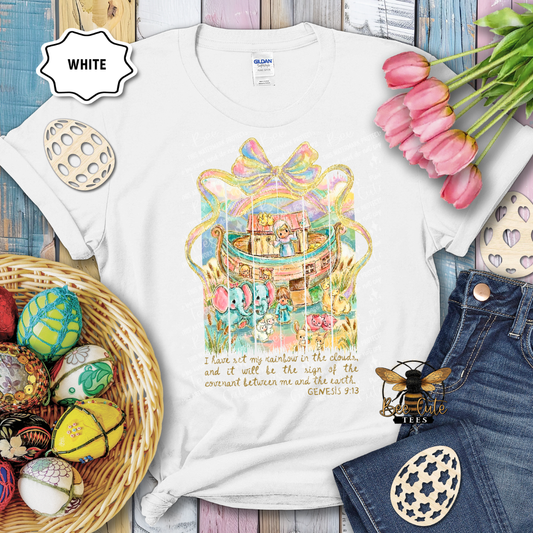White t-shirt with colorful graphic design and Easter decorations on a wooden surface.