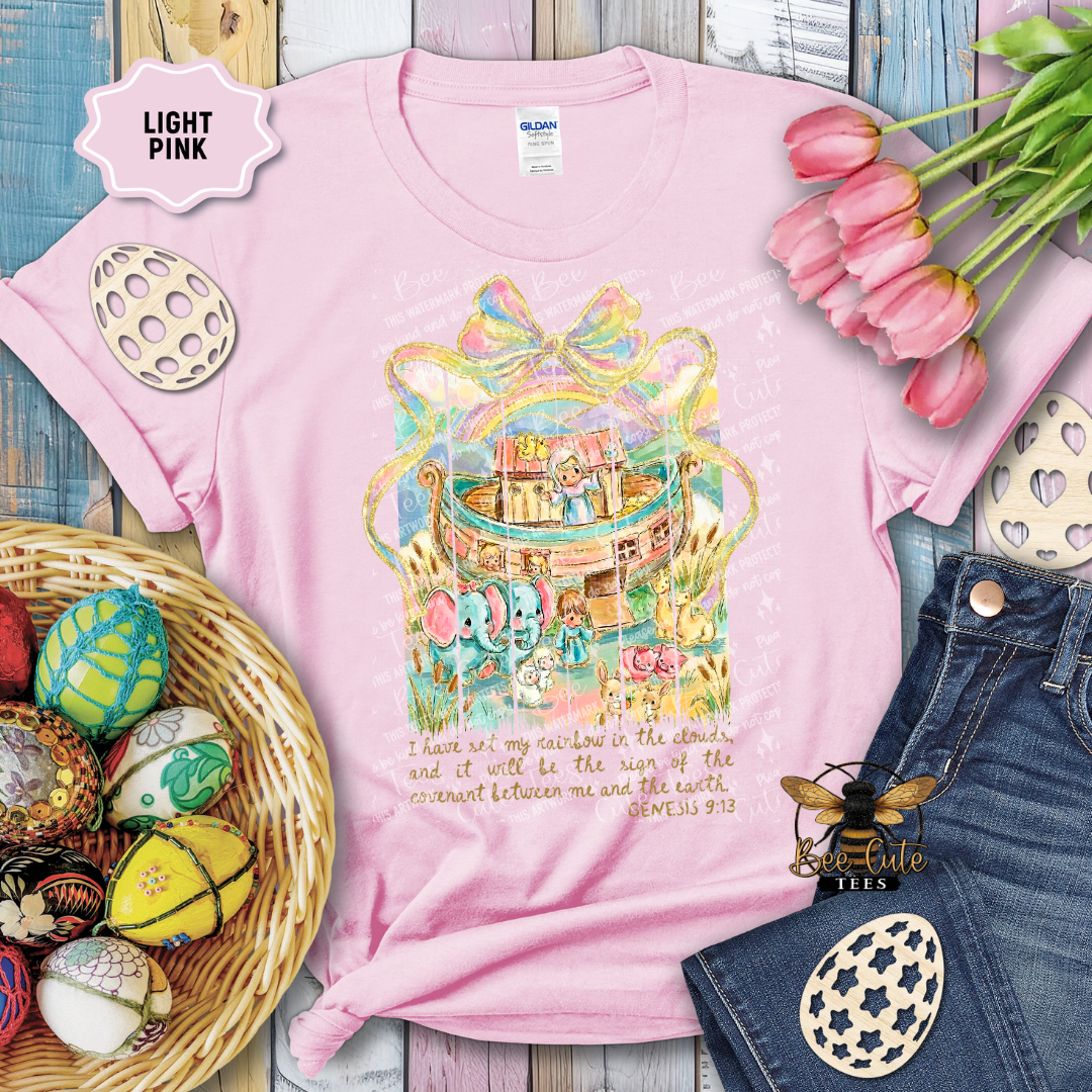 Light pink t-shirt with a colorful graphic design on a wooden surface with Easter decorations.